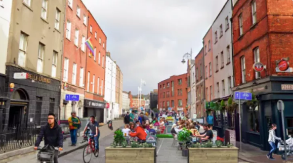 exterior shot of capel street with people cycling and sitting outside bars and restaurants