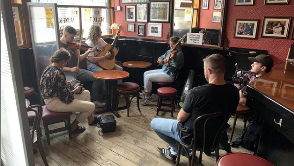 musicians in the corner of a pub playing fiddles, guitars and other trad instruments