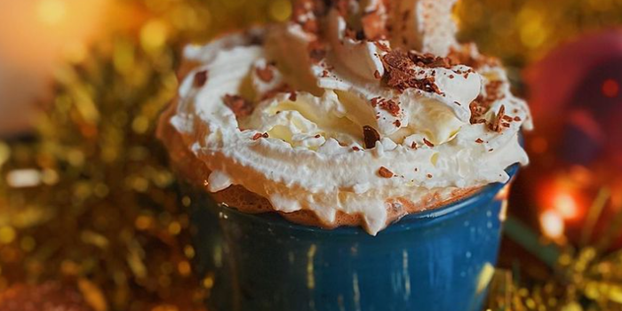 hot chocolate in blue mug with whipped cream on top and chocolate sprinkles