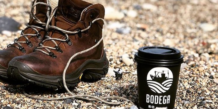 takeaway coffee cup on beach beside shoes