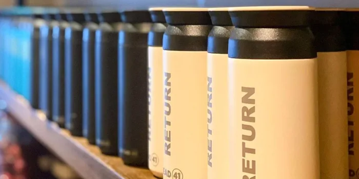 shot of bread 41's keep cups - black and white canister like cups with "return" written on the side