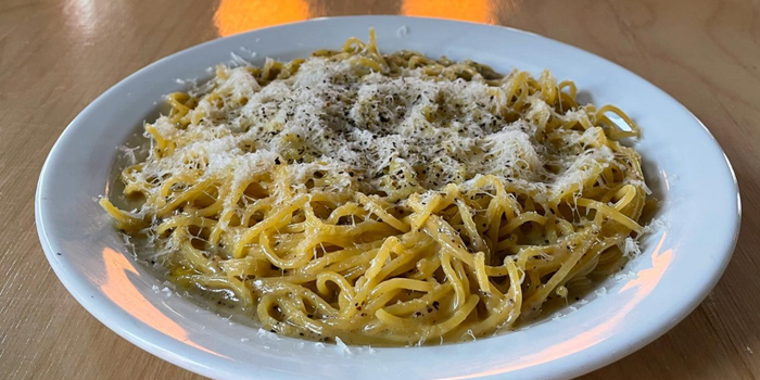 pasta dish cacio e pepe in a white bowl with grated cheese on top
