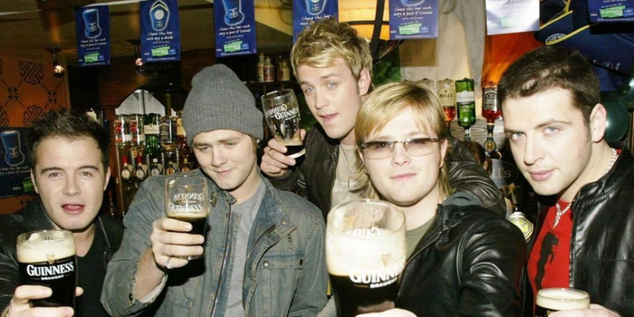 the 5 original members of Westlife in a pub all holding pints of Guinness