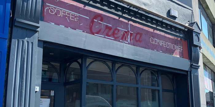 exterior of an old cafe, painted navy, sign reads "Crema" with "coffee" and "confectionary" in smaller font on either side.