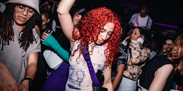 woman with red hair dancing in a nightclub, surrounded by other women