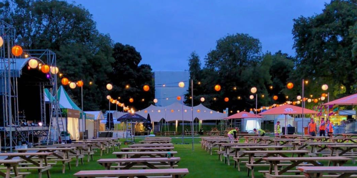 picnic tables, food stalls and fairy lights at dusk at taste of dublin