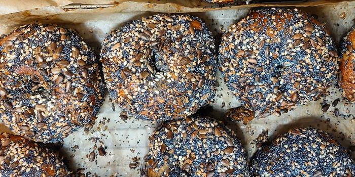 a batch of seeded bagels on a baking tray
