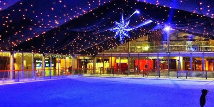 empty iceskating rink at nighttime with a fabric ceiling and fairy lights overhead.