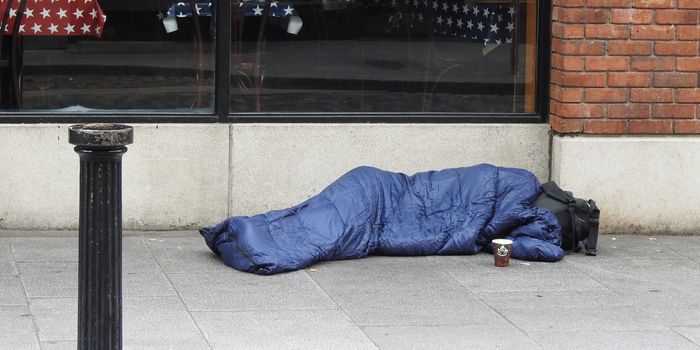 person sleeping in sleeping back with face covered, on the side of a street in Dublin