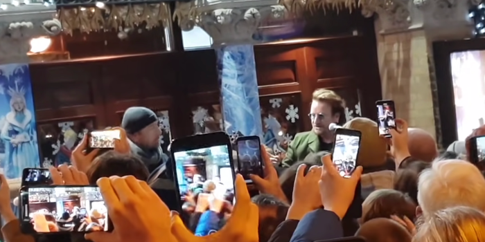 a crowd full of people with camera phones filming bono and the edge busking in dublin