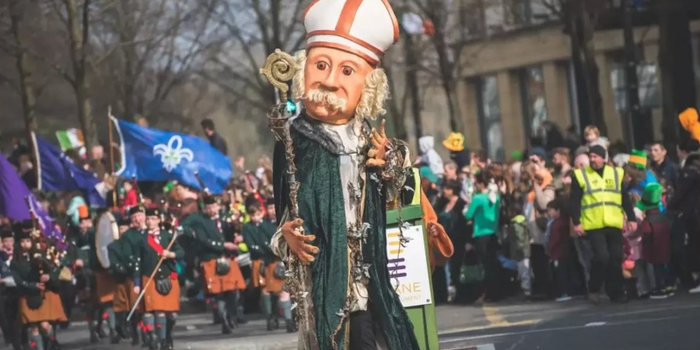 a large puppet version of St Patrick at the Paddys Day parade, with a crowd of people behind barriers