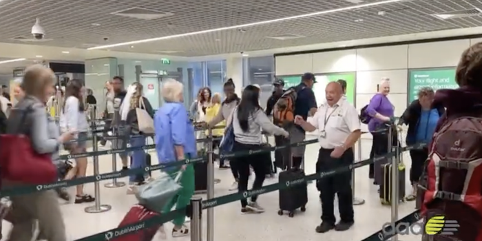 an airport security queue with a security worker dancing jovially in the middle of it