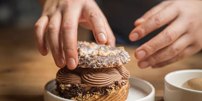 a close up of hands preparing a chocolate dessert