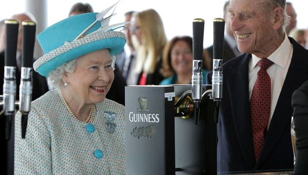 queen elizabeth and prince philip smiling in front of a guinness tap