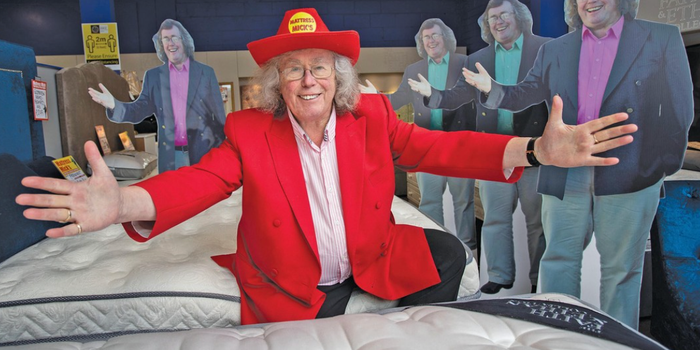 mattress mick posing in a red suit and hat at his mattress shop