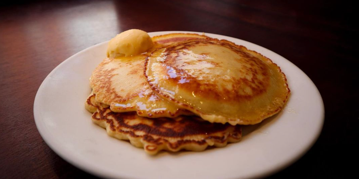 a small stack of pancakes with melted butter on top